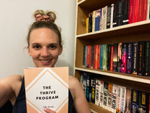 Load image into Gallery viewer, Young woman holding her copy of The Thrive Program and smiling
